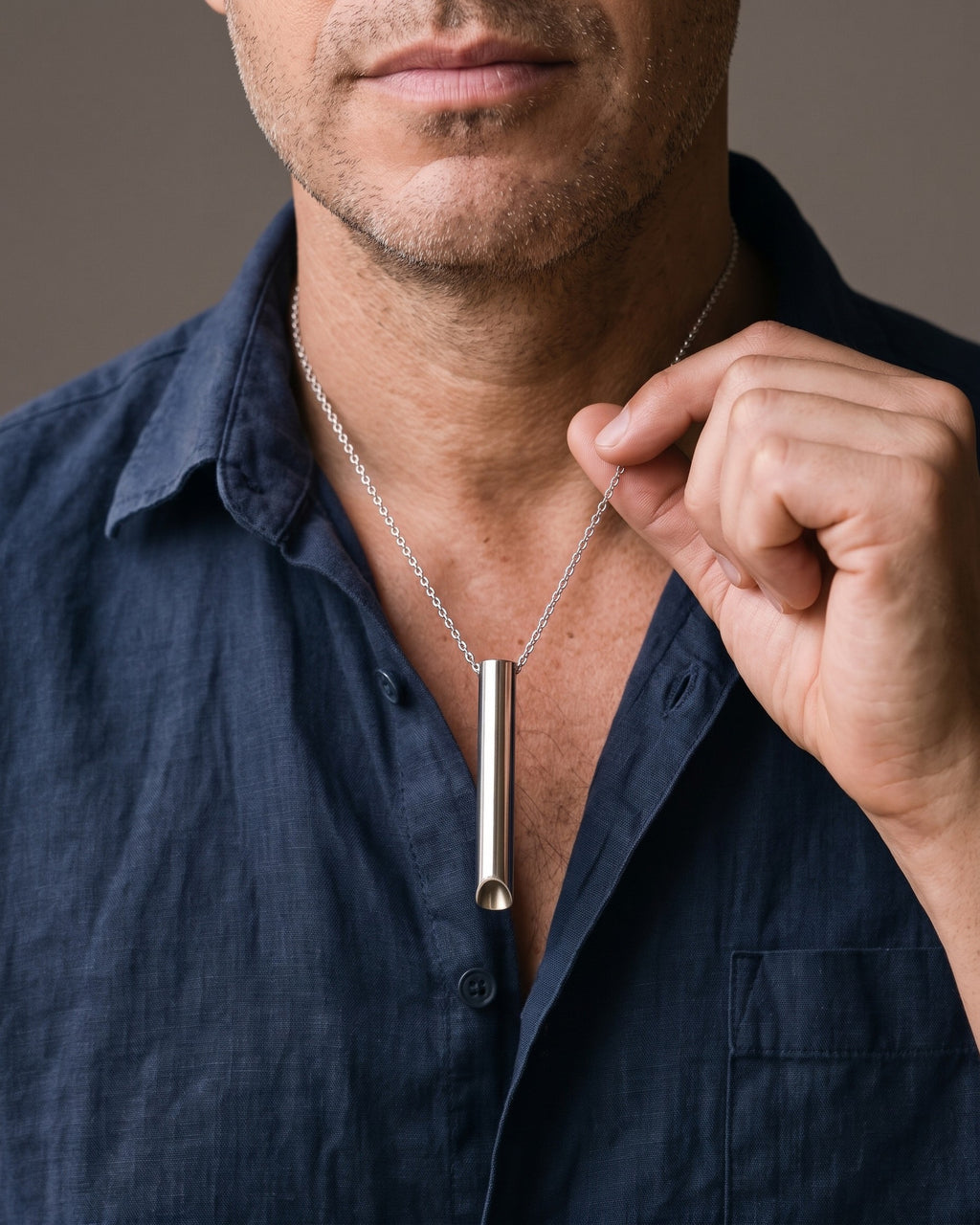 Hand lifting the Atlas Whistle Pendant Necklace in Titanium Steel at the collarbone