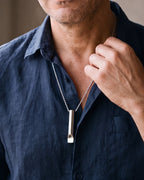 Close-up of the silver Atlas Whistle Pendant Necklace in Titanium Steel worn by a man, shown at true size