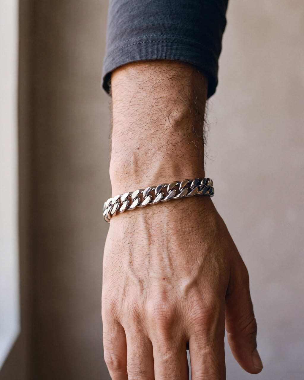 Close-up of the silver Atlas wide Cuban link bracelet worn by a man, shown at true size
