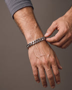Hand adjusting the Atlas Wide Cuban Link Bracelet in Titanium Steel on the wrist