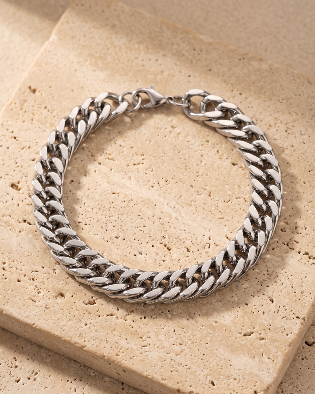 The whole silver Atlas wide Cuban link bracelet laid on warm stone