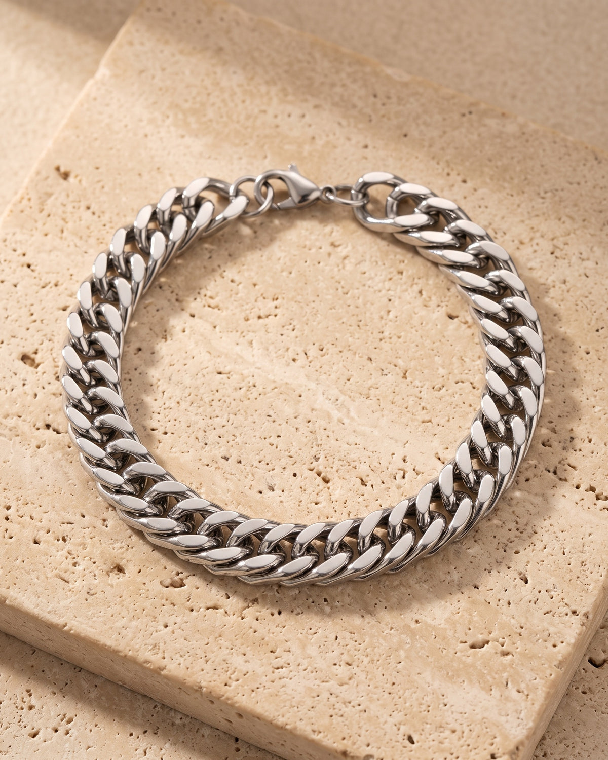 The whole silver Atlas wide Cuban link bracelet laid on warm stone