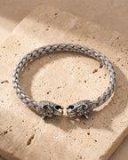 The whole silver-tone Atlas wolf head braided cuff bracelet lying on warm travertine stone