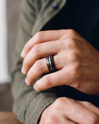 Close-up of the black Atlas wood and abalone band in black tungsten worn by a man, shown at true size