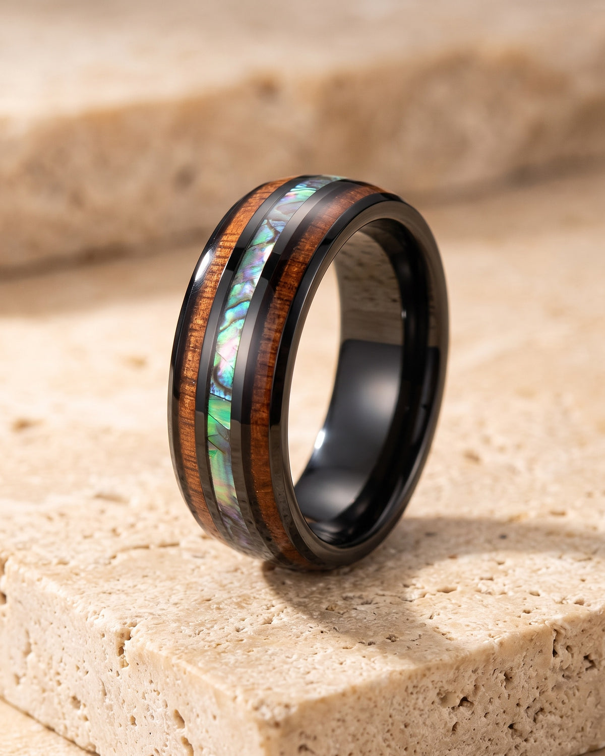 The whole black Atlas wood and abalone band in black tungsten laid on warm stone