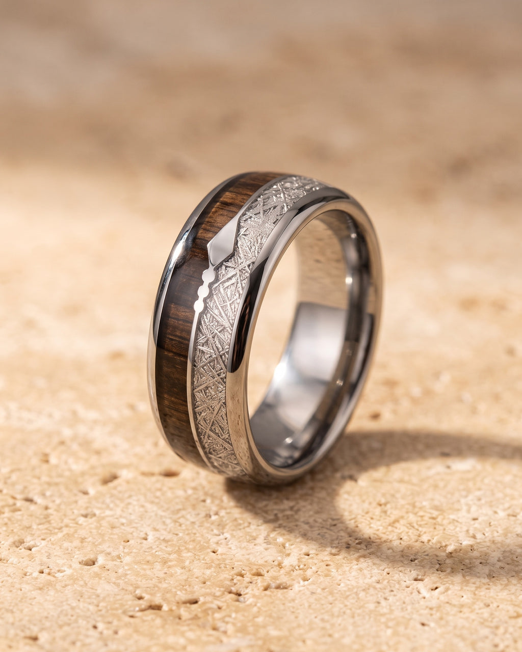 Entire Atlas wood and meteorite-look inlay tungsten ring in silver-tone steel, lying flat on warm stone