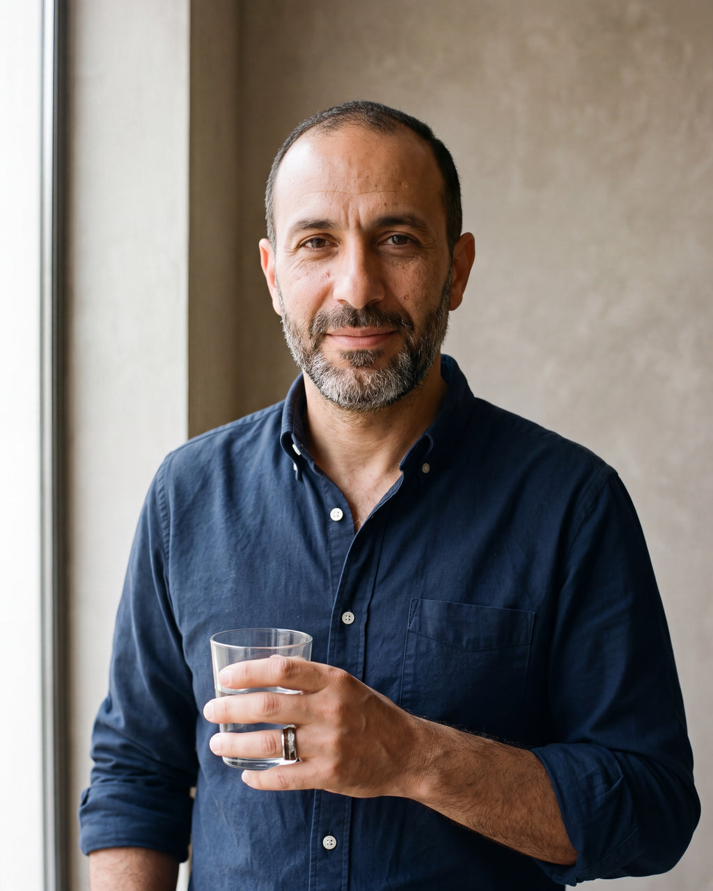 Man in a navy oxford shirt wearing the Atlas wood and meteorite-look inlay tungsten ring in silver-tone steel