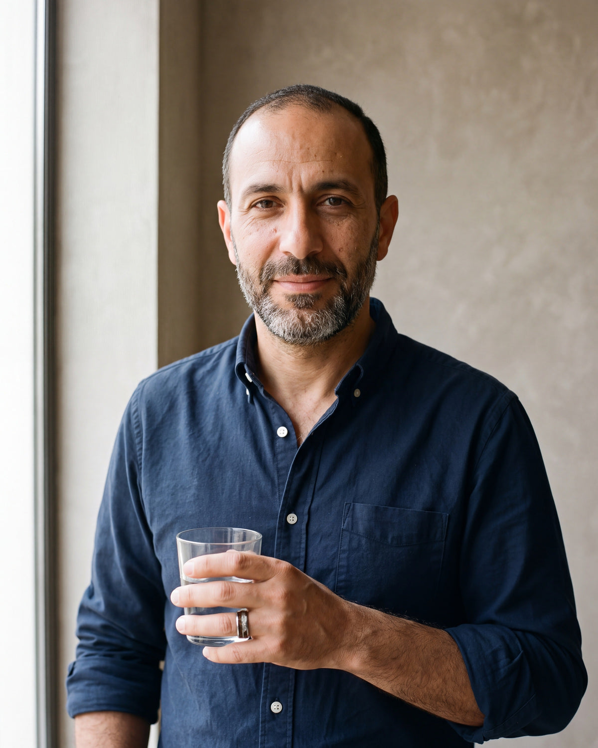 Man in a navy oxford shirt wearing the Atlas wood and meteorite-look inlay tungsten ring in silver-tone steel