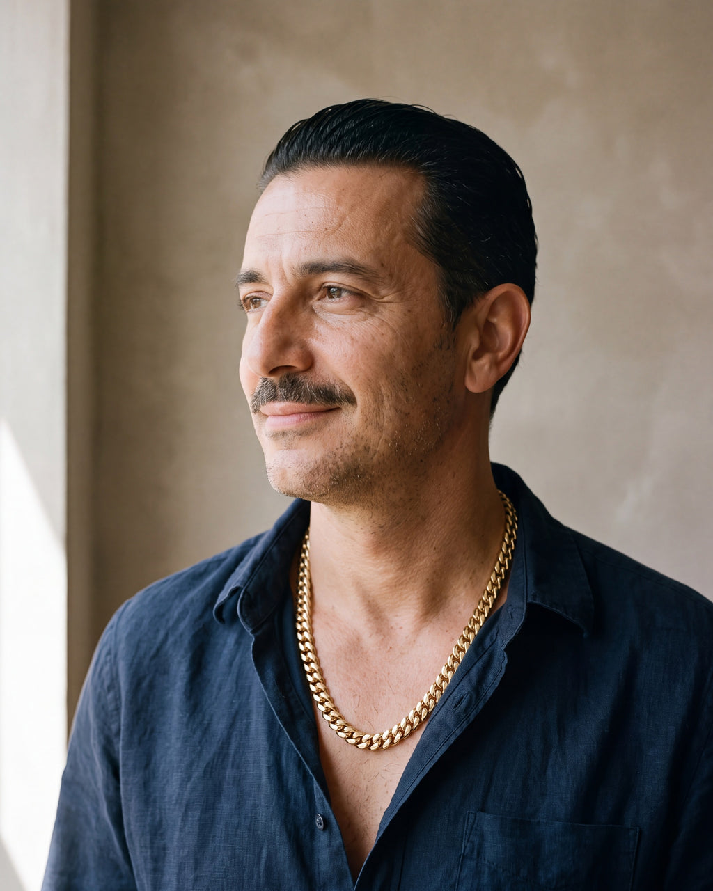 Man in a navy linen shirt wearing the Atlas Cuban chain with zircon cross clasp in gold-tone steel