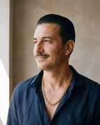 Man in a navy linen shirt wearing the Atlas Cuban chain with zircon cross clasp in gold-tone steel