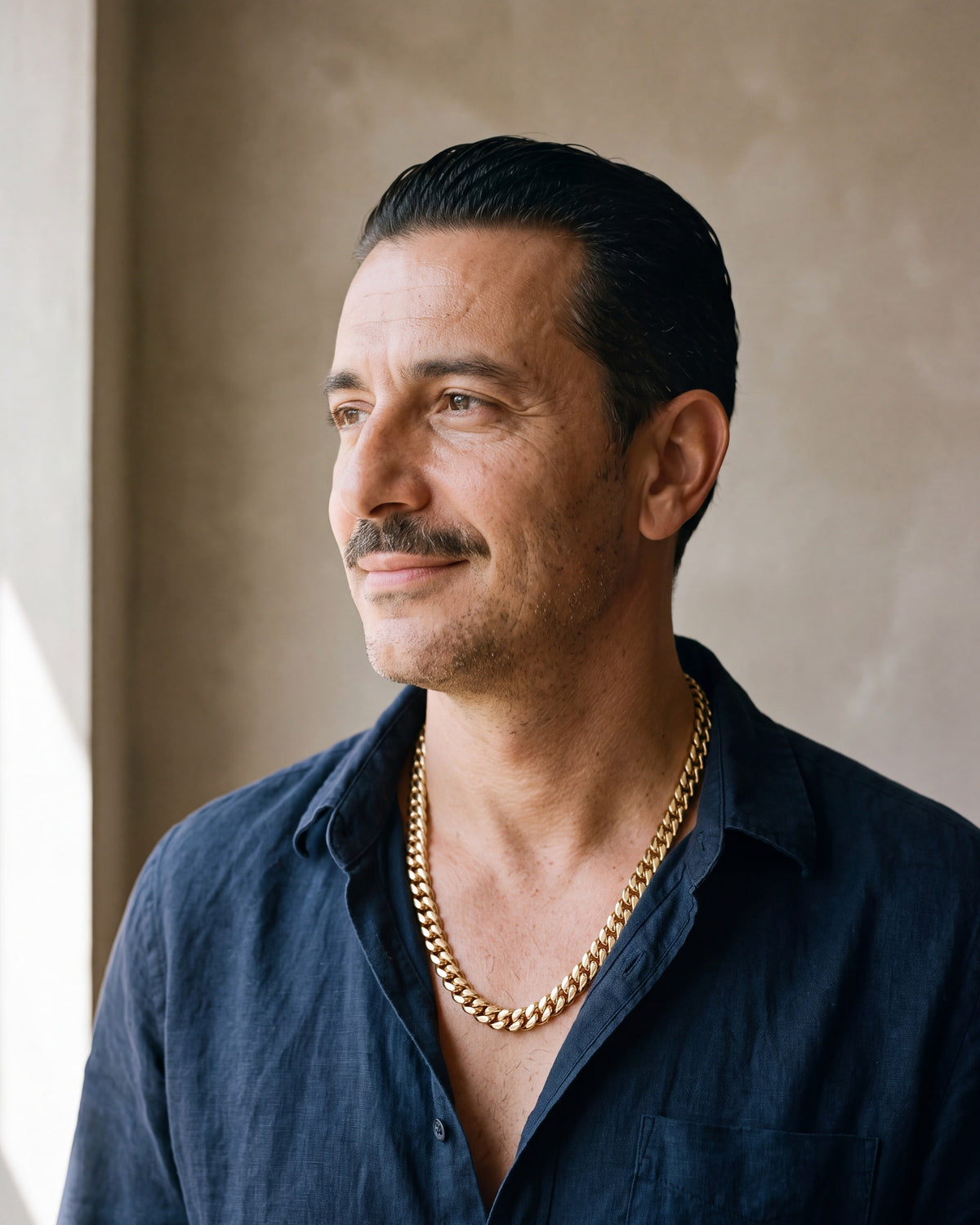 Man in a navy linen shirt wearing the Atlas Cuban chain with zircon cross clasp in gold-tone steel