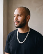 Man in a black t-shirt by a window wearing the Atlas Cuban chain with zircon cross clasp in silver-tone steel