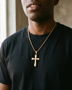 Atlas zircon cross pendant necklace in gold-tone titanium steel worn on the chest, close-up