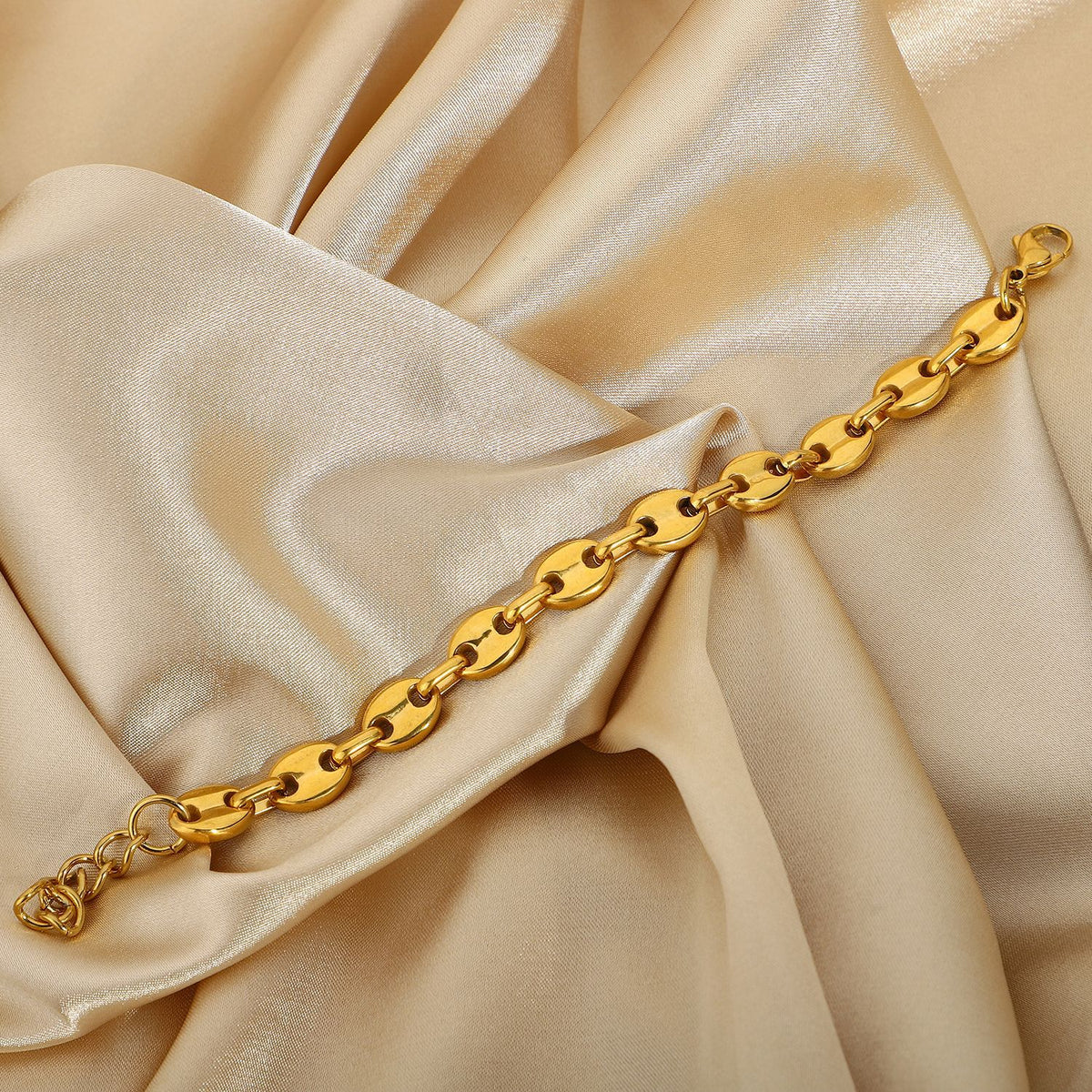 Gold-Tone Coffee Bean Link Bracelet on a light gold fabric background