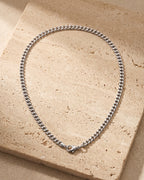 Silver Atlas 3 mm Cuban chain laid whole on warm stone, lobster clasp closed