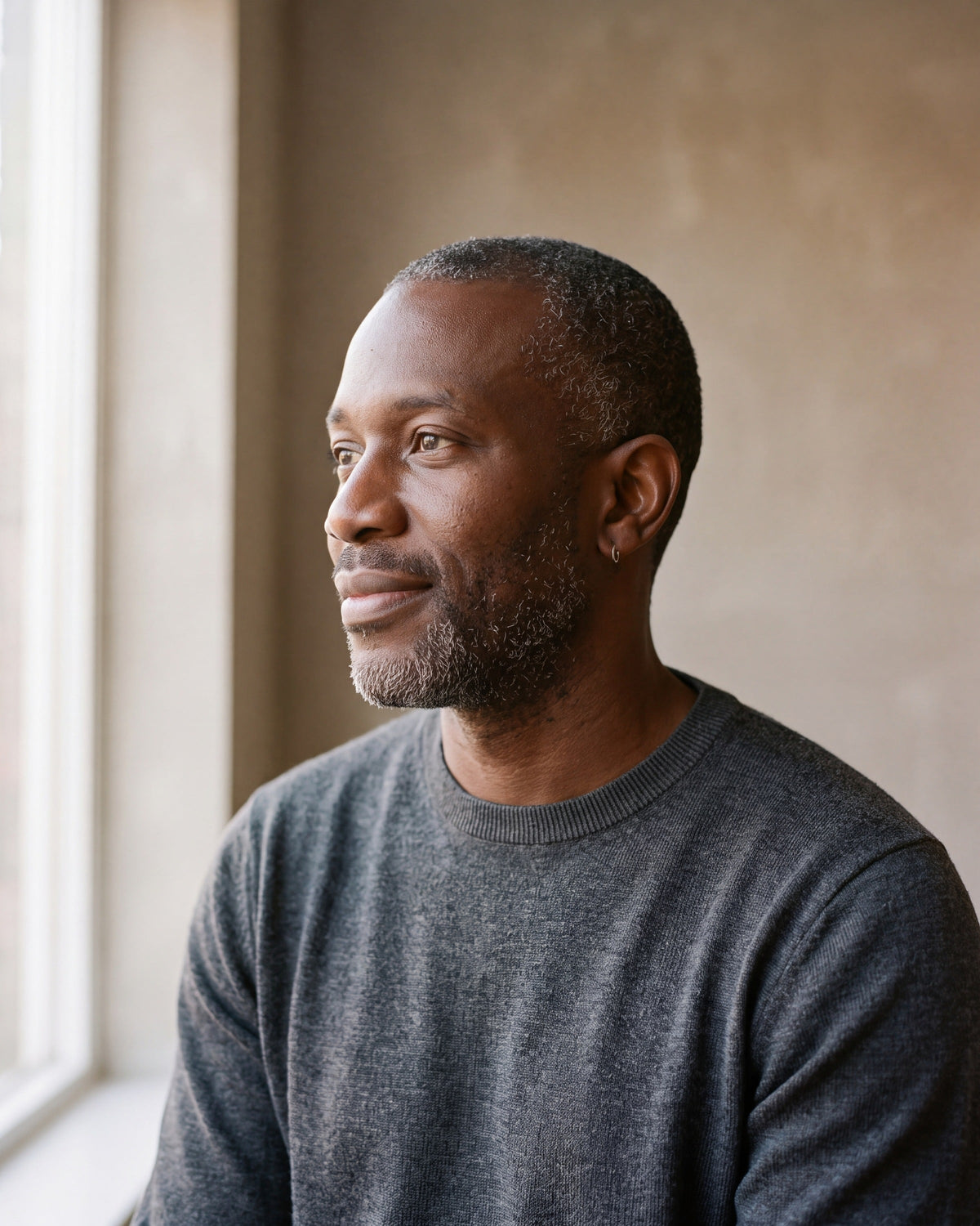 Man in a charcoal sweater seen in profile wearing the silver-tone Atlas thin seamless hoop earrings